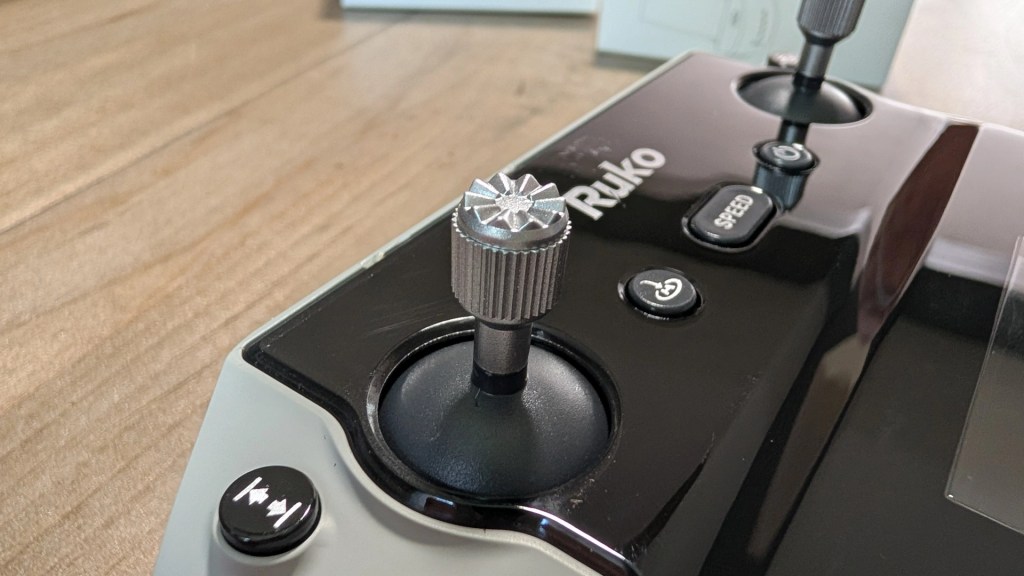 Close-up of a Ruko device showing control knobs, buttons, and a sleek surface on a wooden table.