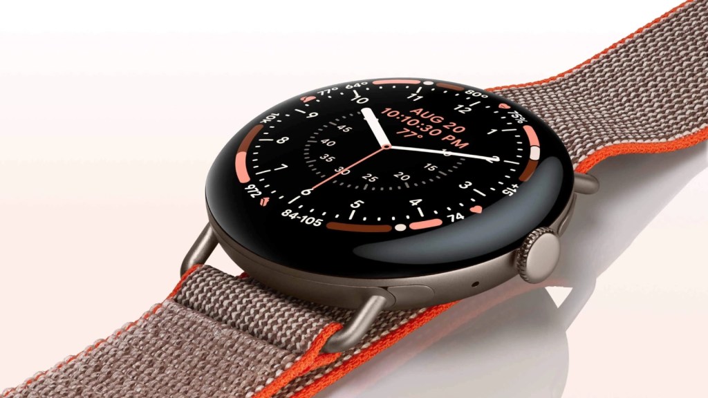 A smartwatch displaying the date, time, and health metrics, featuring a dark screen with colorful indicators and a grey fabric strap with orange accents.