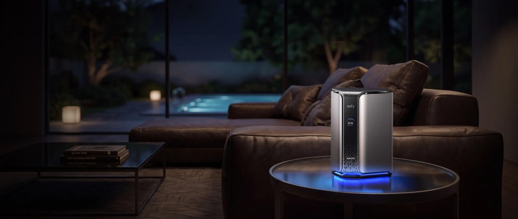 A modern air purifier with a sleek design and blue lighting, placed on a circular table in a dimly lit living room, with a cozy couch and a view of a pool in the background.