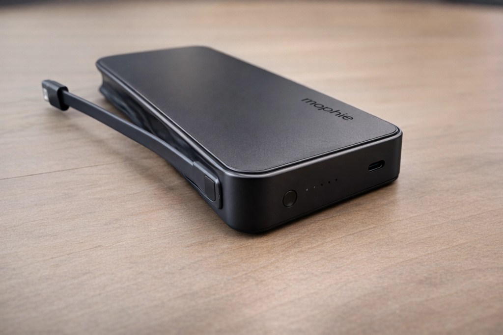 A Mophie portable charger with a sleek black design, featuring a built-in charging cable and an indicator light showing battery status.