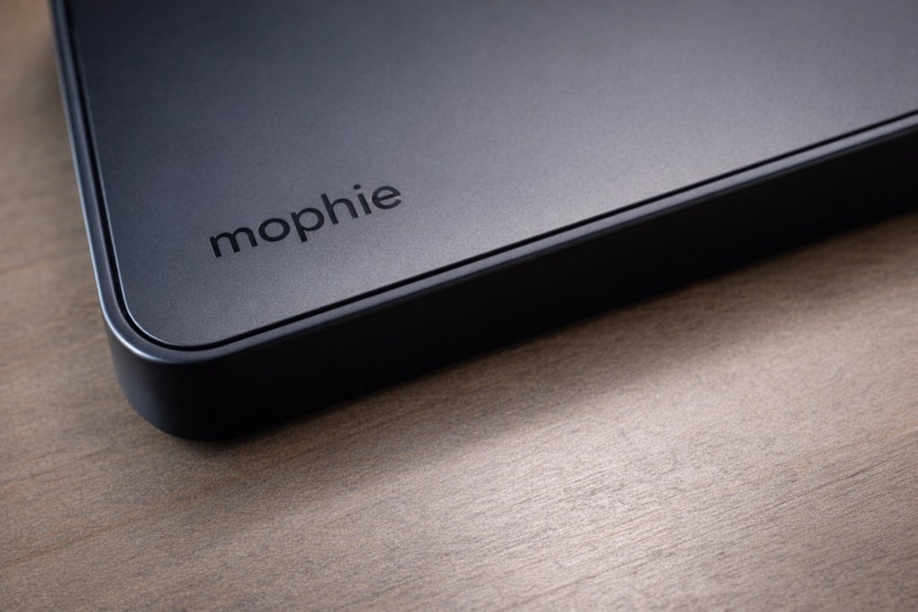 Close-up of a black Mophie charging pad on a wooden surface, showcasing the brand name.