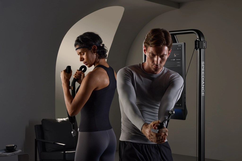 A man and a woman engaged in a workout session using resistance bands in a modern fitness setting.